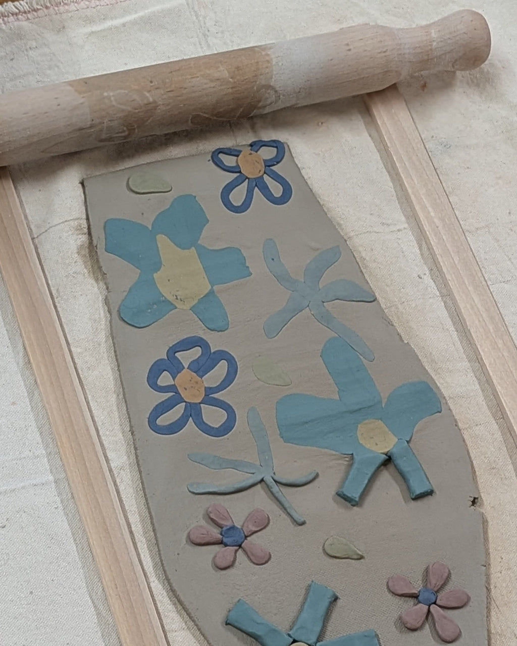 Flower-shaped cutouts on a wooden board with a rolling pin